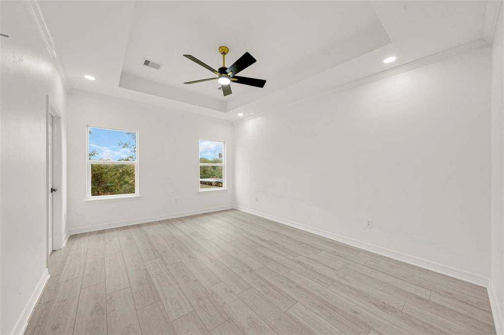 Spacious primary bedroom with large windows and direct access to ensuite bathroom.