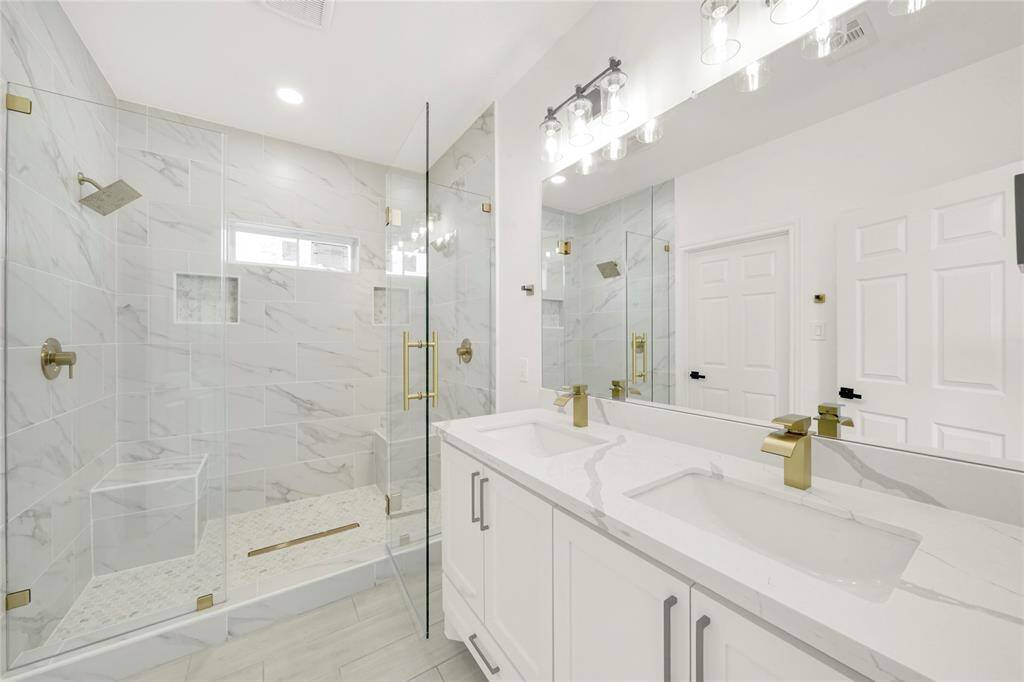 Elegant primary bathroom featuring double sinks, quartz countertops, and modern fixtures