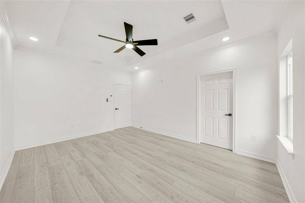 Another bright bedroom with ceiling fan and large window.