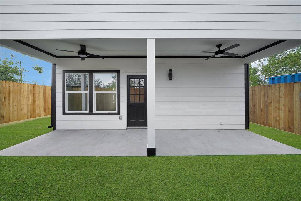 Covered back patio with grassy yard, perfect for outdoor relaxation or play.