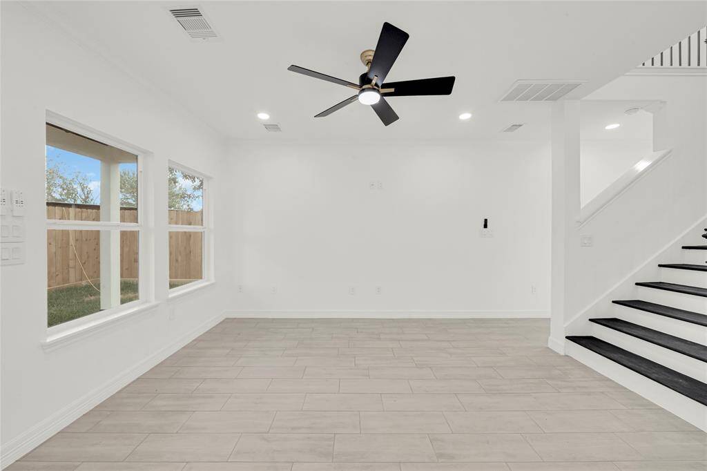View of sleek staircase leading to upstairs, complemented by natural light and ceiling fan.