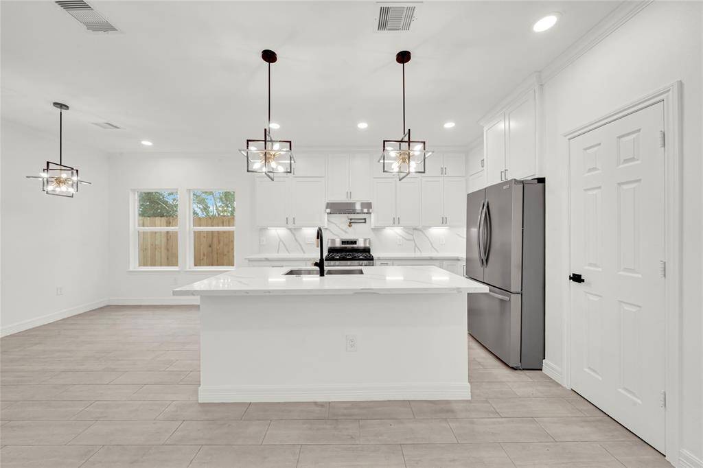 Bright dining space with views of the backyard, next to stylish kitchen with custom cabinetry.
