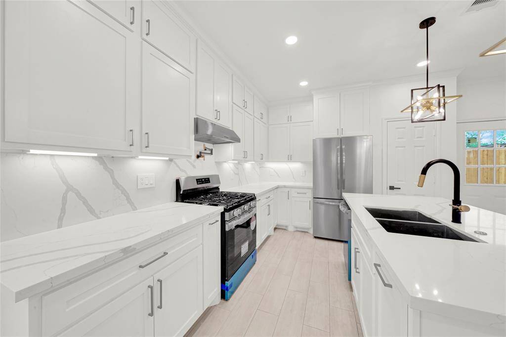 Close-up of gas cooktop, under-cabinet lighting, and modern tile backsplash.