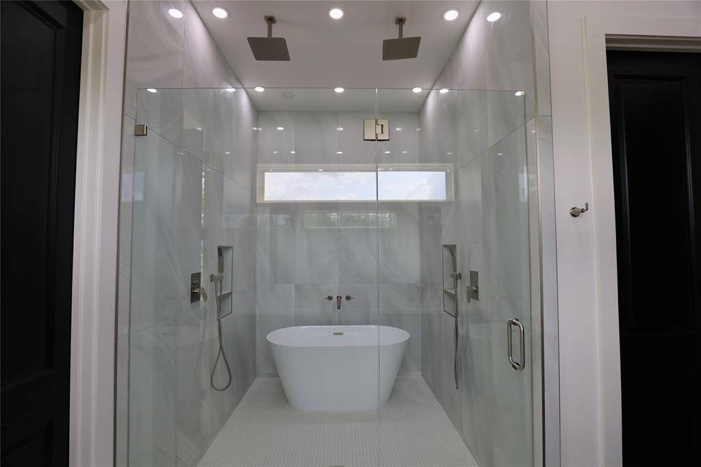 A spa-inspired shower featuring a rainfall showerhead, floor-to-ceiling tiles, a handheld sprayer, and his and hers fixtures for the ultimate in indulgence.