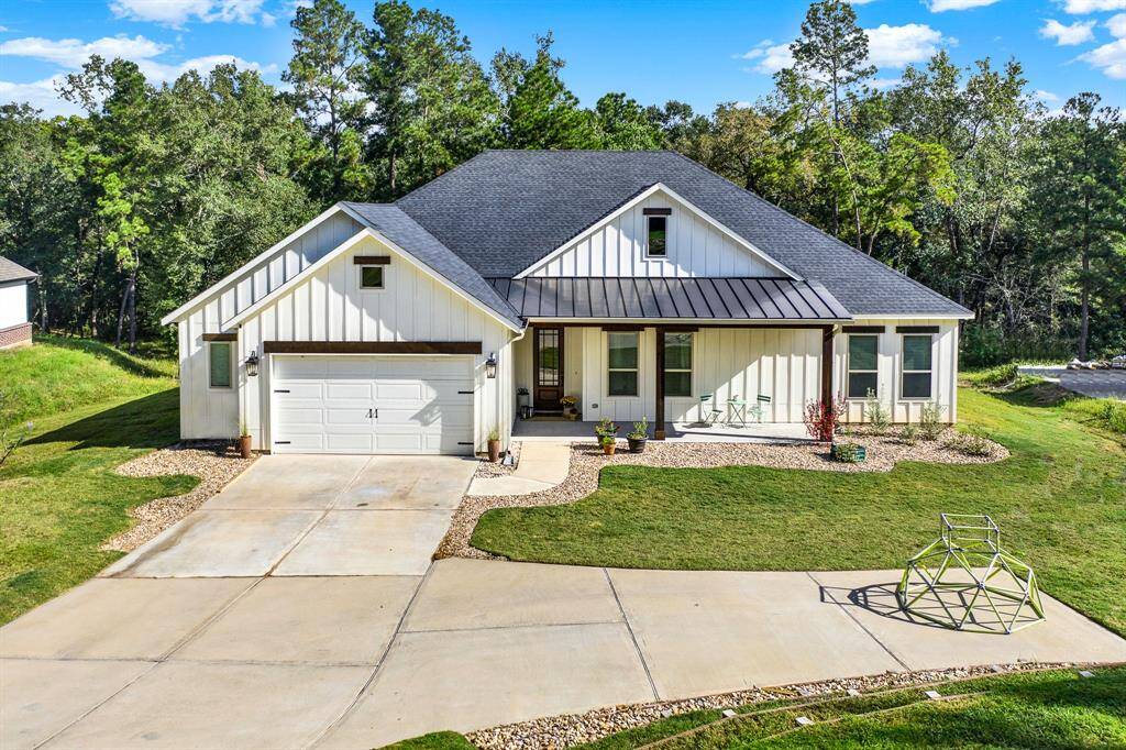 This single-story home has a a welcoming front porch ready for rocking chairs or additional plants or flowers to make it even more serene. The property is surrounded by a relaxing wooded backdrop.