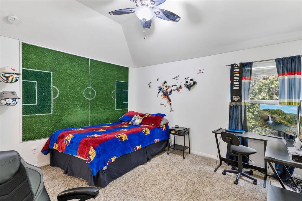 A vibrant children's room featuring a soccer theme with a field mural wall, colorful bedding, and sports decor. The space includes a desk, chair, and shelving, with a window providing natural light. Ideal for a sports enthusiast.