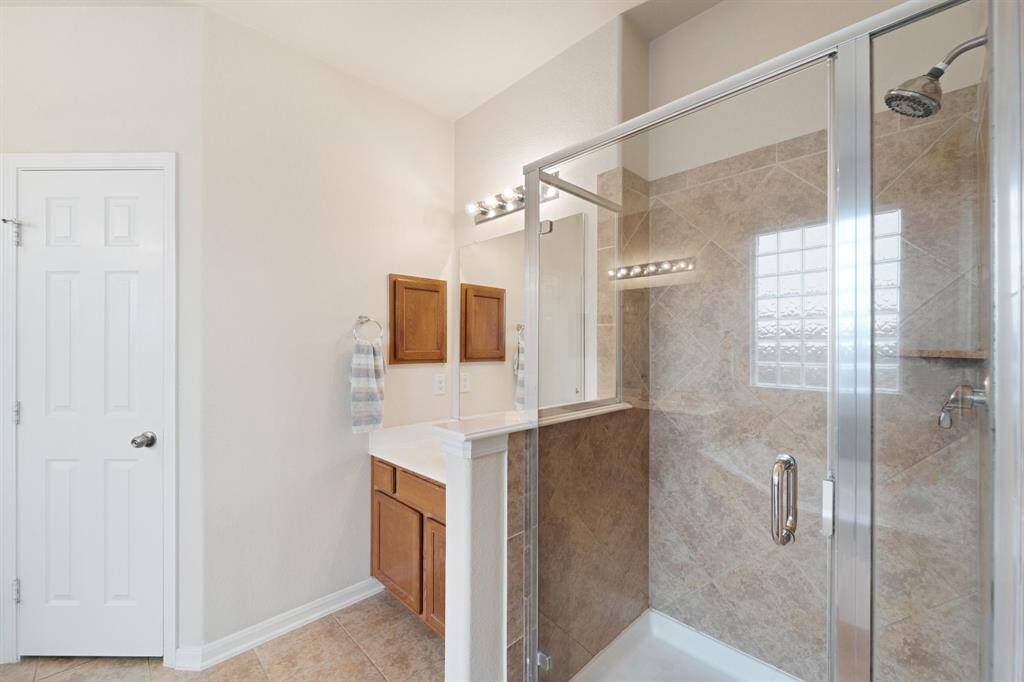 Beautifully tiled walk-in shower with glass enclosure and private vanity area—perfect for busy mornings.