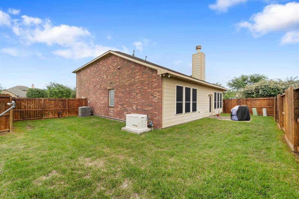 Spacious backyard with grassy area and plenty of room for play or pets, plus a view of the home’s brick and siding exterior.