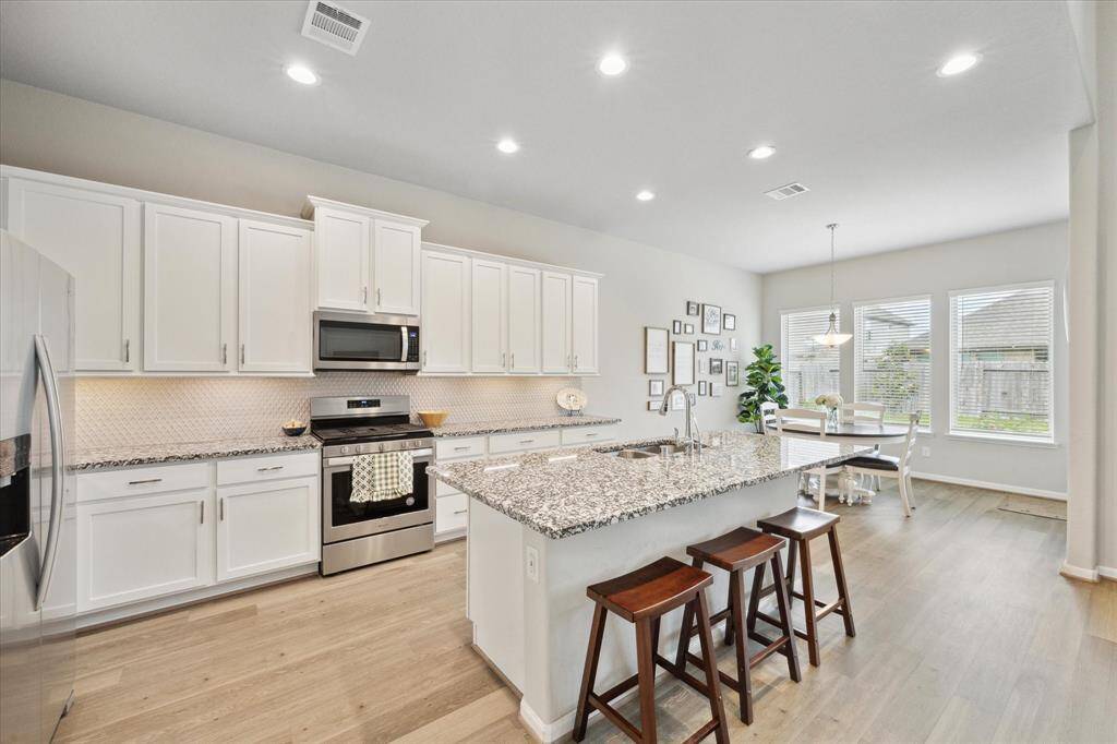 Granite countertops, stainless steel appliances, white cabinets and recessed lighting make cooking in this kitchen enjoyable.