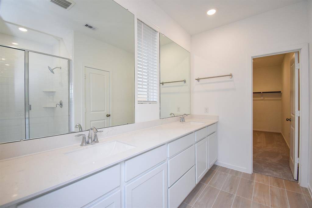 Elegant primary bathroom featuring a spacious double vanity, sleek fixtures, and a bright, airy ambiance.