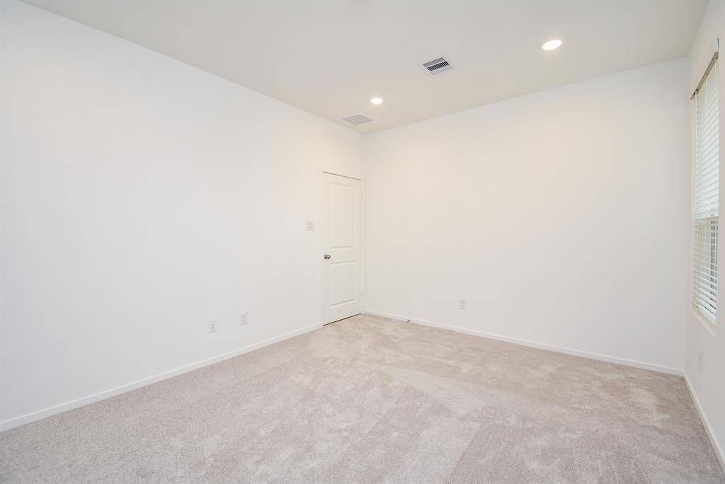 Bright and inviting secondary bedroom with plush carpet and ample natural light from two large windows.
