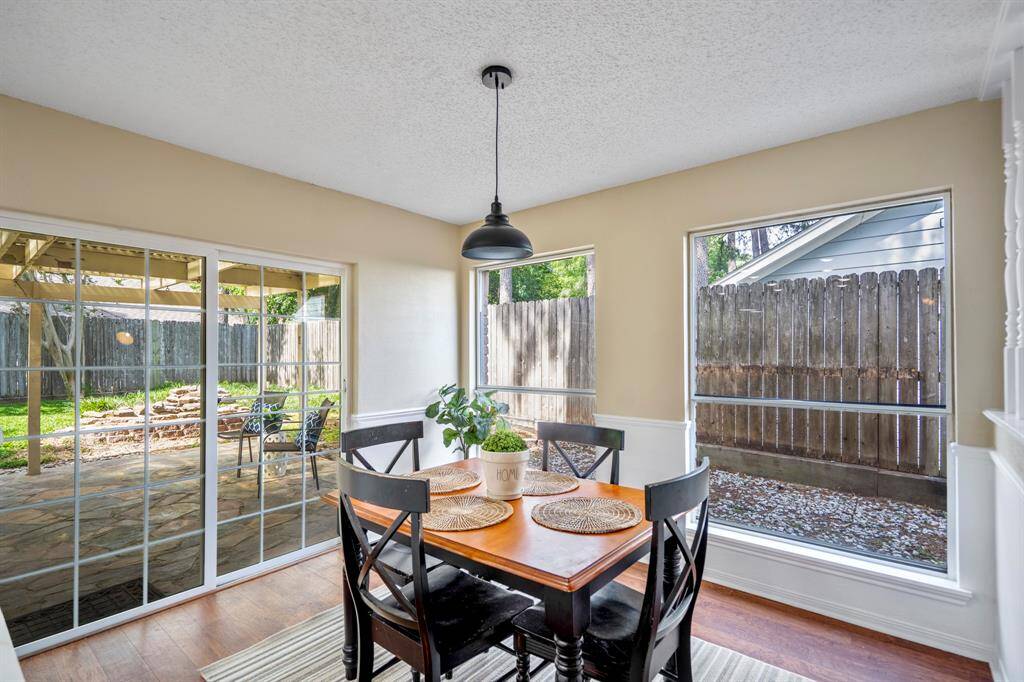 Bright and inviting, the breakfast nook features large windows that fill the space with natural light. To the left, a sliding glass door opens directly to the covered flagstone patio, perfect for indoor-outdoor living.