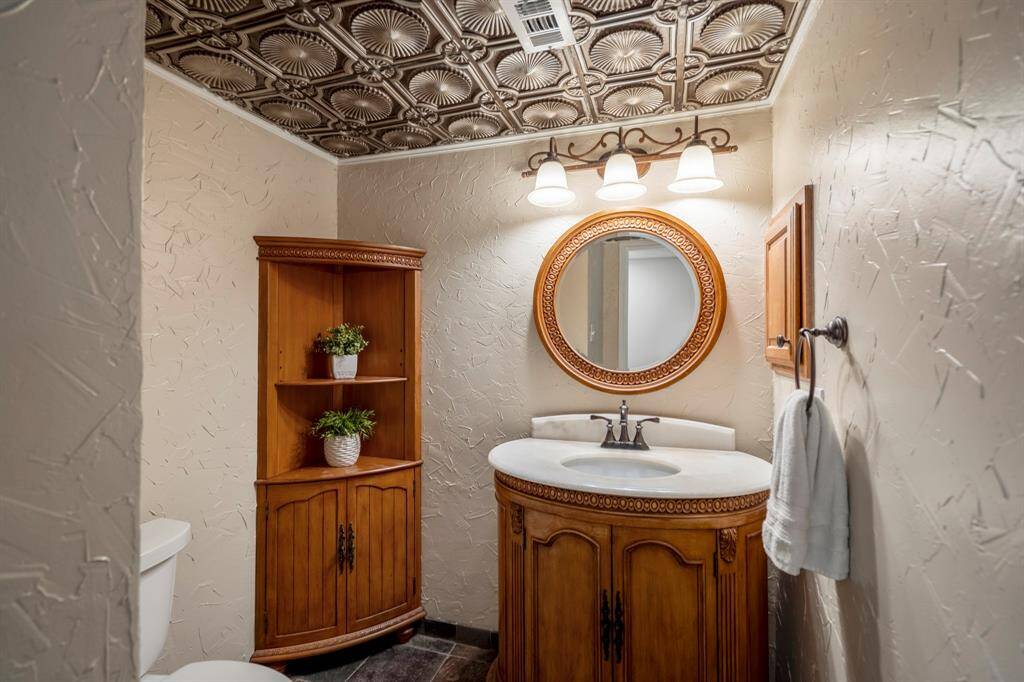 This stylish half bath showcases a decorative accent ceiling and slate-style tile flooring, adding a touch of personality and charm to a functional space.