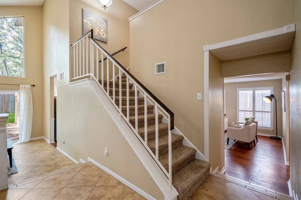 Standing at the base of the staircase, you see the formal dining room to the left and the family room through the doorway to the right—welcoming views of the home’s open, connected living spaces before heading upstairs.