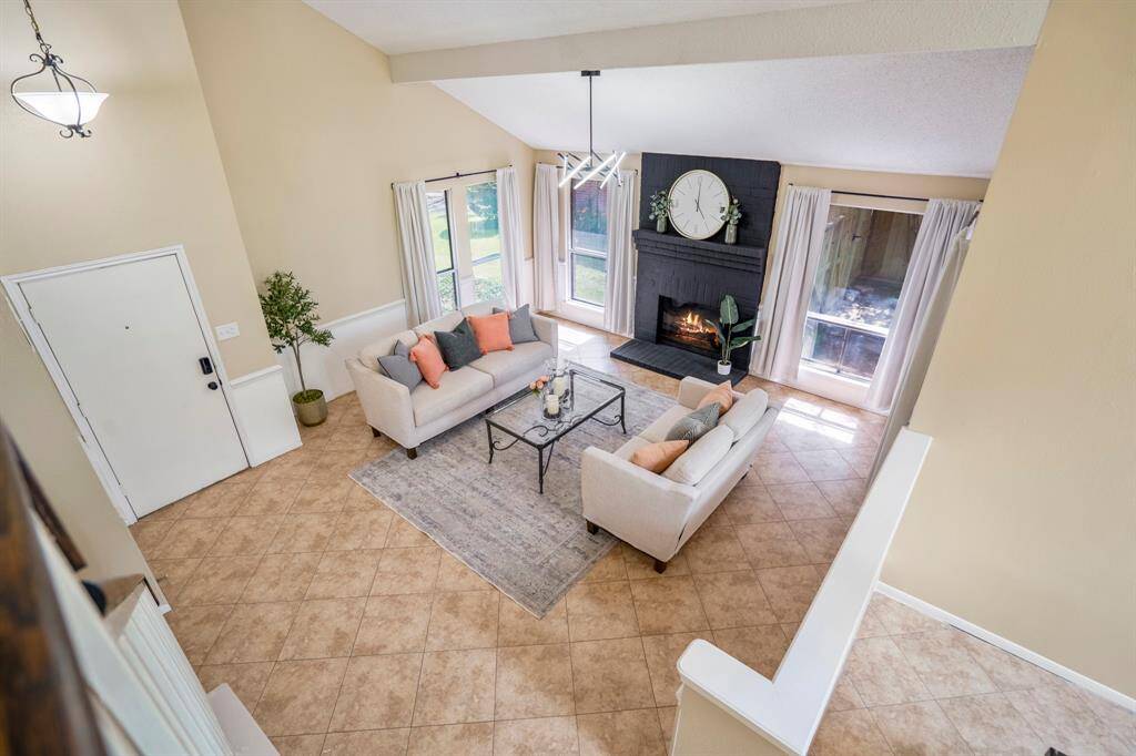 Looking down from the stairs, the formal living area unfolds below with its vaulted ceilings, while the formal dining room peeks into view—offering a unique perspective on the home’s elegant entertaining spaces.
