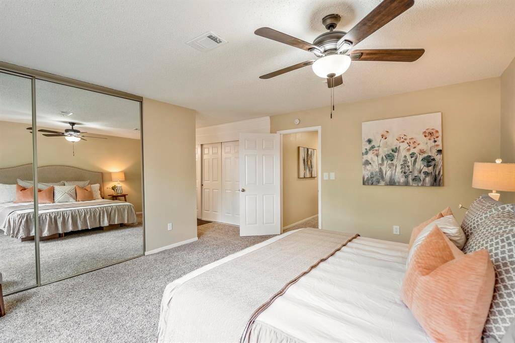 From this corner of the primary bedroom, the spacious closet with mirrored sliding doors is visible, along with the doorway to the bathroom and a second closet with sliding doors—offering ample storage and easy flow.