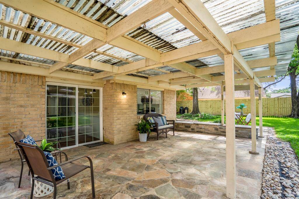 Standing at the edge of the covered patio and looking to the left, we take in the expanse of the lush backyard. The flagstone patio flows seamlessly into the green lawn, and the recently installed fencing along the left side adds a fresh touch of privacy and polish.