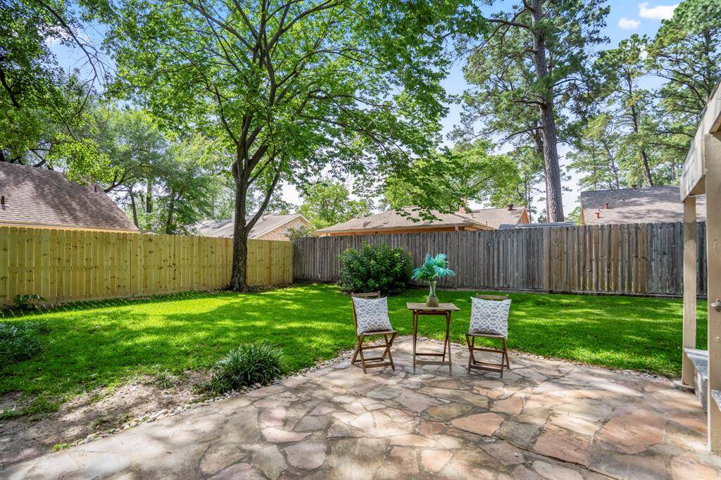 A closer look at the uncovered flagstone patio just outside the formal dining room offers a glimpse of the space for outdoor dining or lounging under the open sky. To the left, fresh fencing adds privacy and polish, while the covered patio sits just out of view to the right.