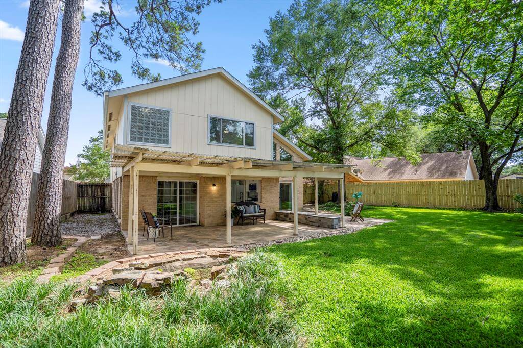 From the corner behind the fountain area, we take in a full view of the home’s rear elevation. The mix of covered and uncovered flagstone patios, lush lawn, and mature landscaping give a sense of the backyard’s charm and potential.