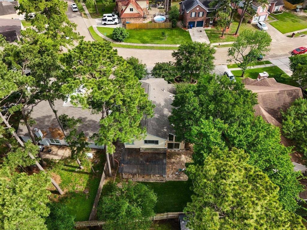 An aerial view from just above the backyard showcases the spacious lot, lush green lawn, and the balance of shaded and sunny outdoor living areas. You can clearly see the layout of the covered and uncovered patios, creating a private outdoor retreat nestled within the neighborhood.