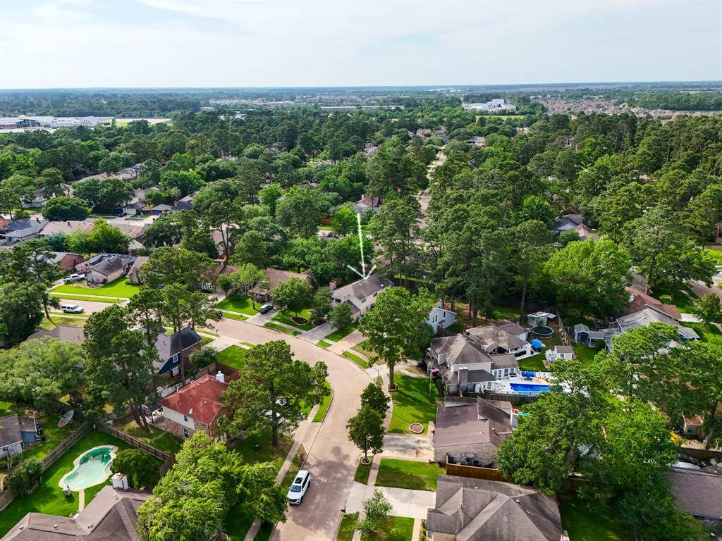 This aerial view, taken from farther down the street, shows how the home is nestled into the curve of the road—offering a unique placement that enhances privacy and curb appeal. You can truly appreciate the established feel of the neighborhood from this angle.