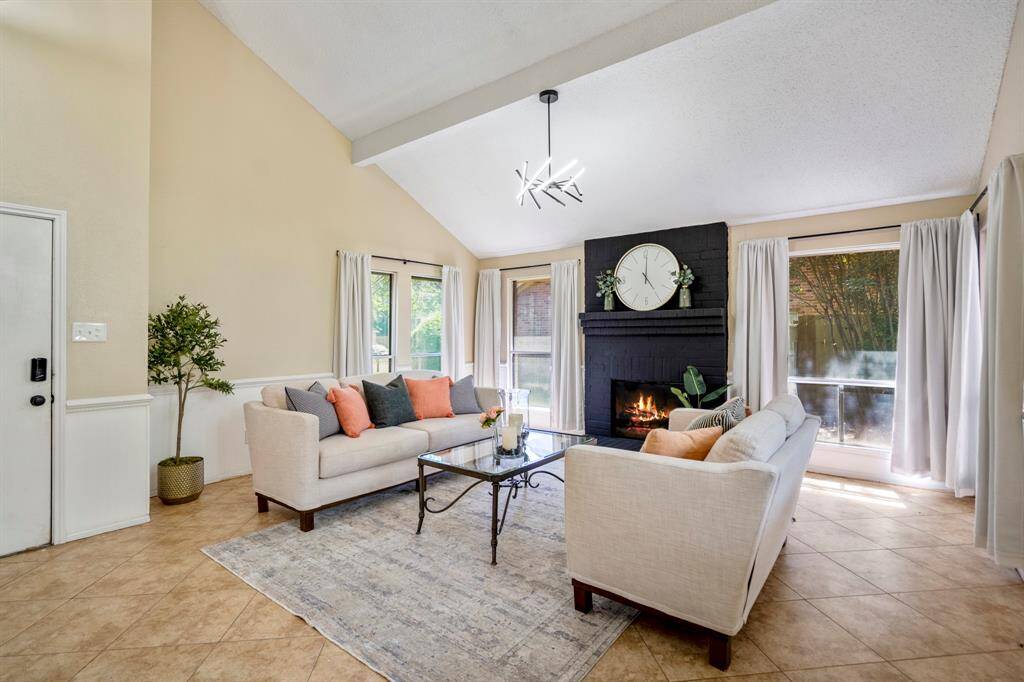 From this view, you can truly appreciate the openness of the formal living room—surrounded by windows on three sides, finished with chair railing, tile floors, and a modern light fixture that adds a contemporary touch.