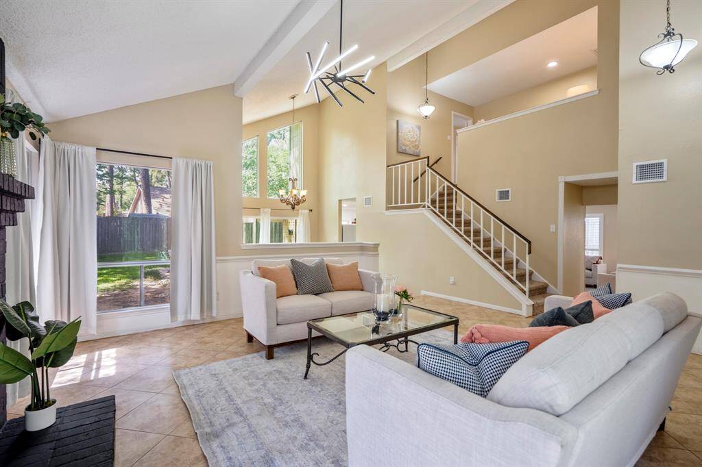 From the front corner of the living room, the open flow becomes clear—catch a glimpse of the sunken family room beyond the staircase, and across the staircase, easy access to the kitchen through the formal dining room. Soaring ceilings and expansive windows enhance the contemporary atmosphere throughout.