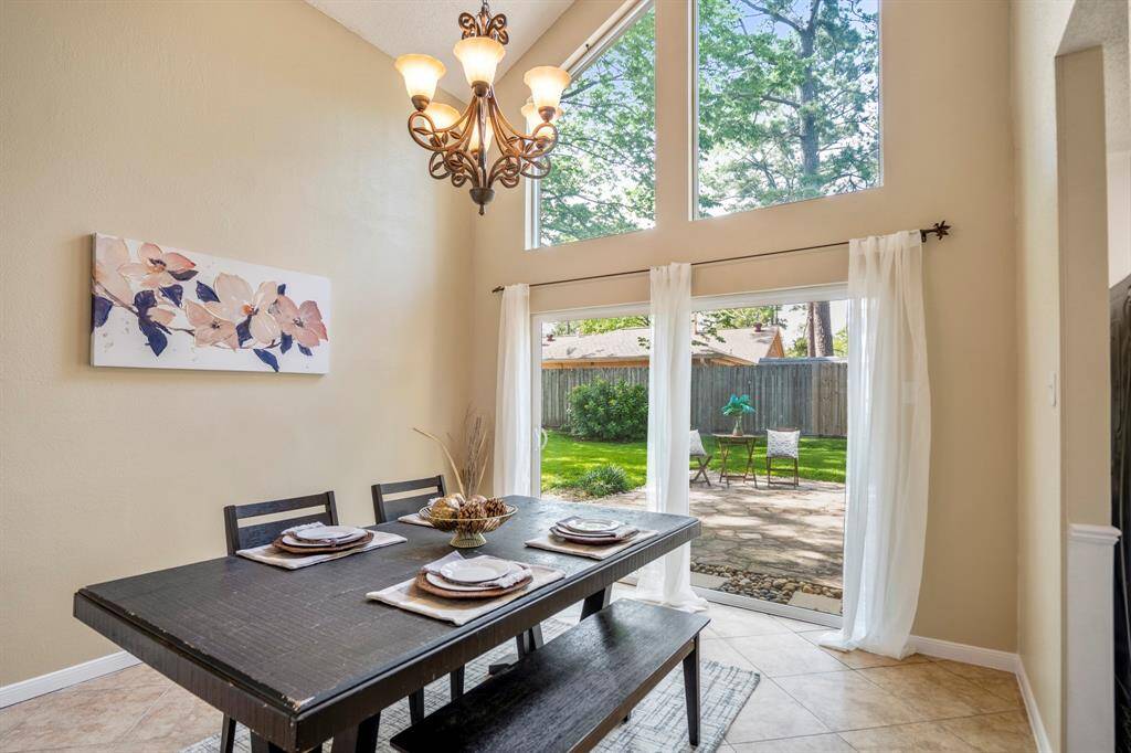 Step down into the sunken formal dining room, where soaring windows flood the space with light and a sliding glass door opens directly to the covered flagstone patio—perfect for seamless indoor-outdoor living.