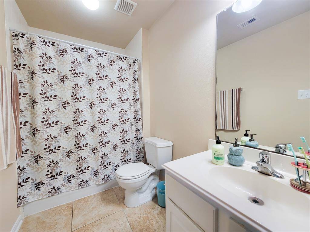 This bedroom is bright and inviting, with neutral walls, a ceiling fan, and a cozy carpeted floor.