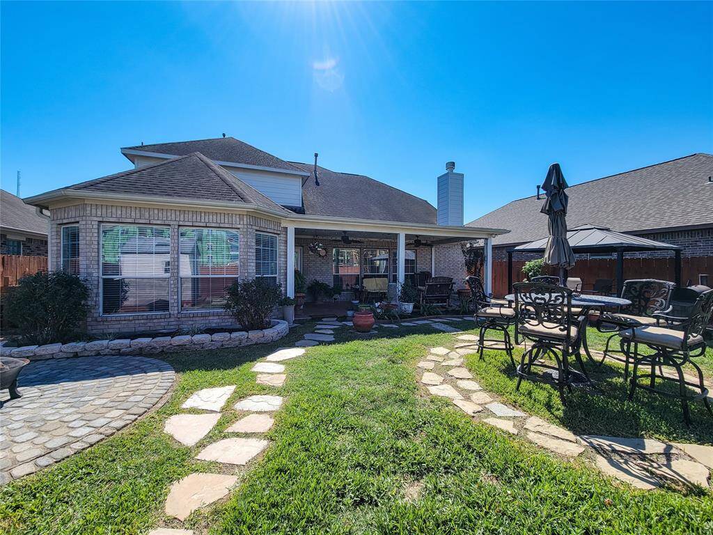 Charming backyard with a covered patio, paved stone path, and outdoor seating area. Ideal for relaxation and entertaining.