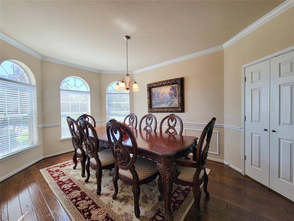 This dining room features elegant hardwood flooring. There's a classic chandelier and tasteful wall art, creating a warm, inviting atmosphere.