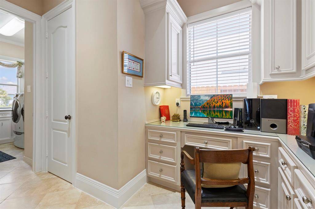 This photo showcases a compact home office setup with built-in cabinets and drawers, a large window providing natural light, and a workspace.