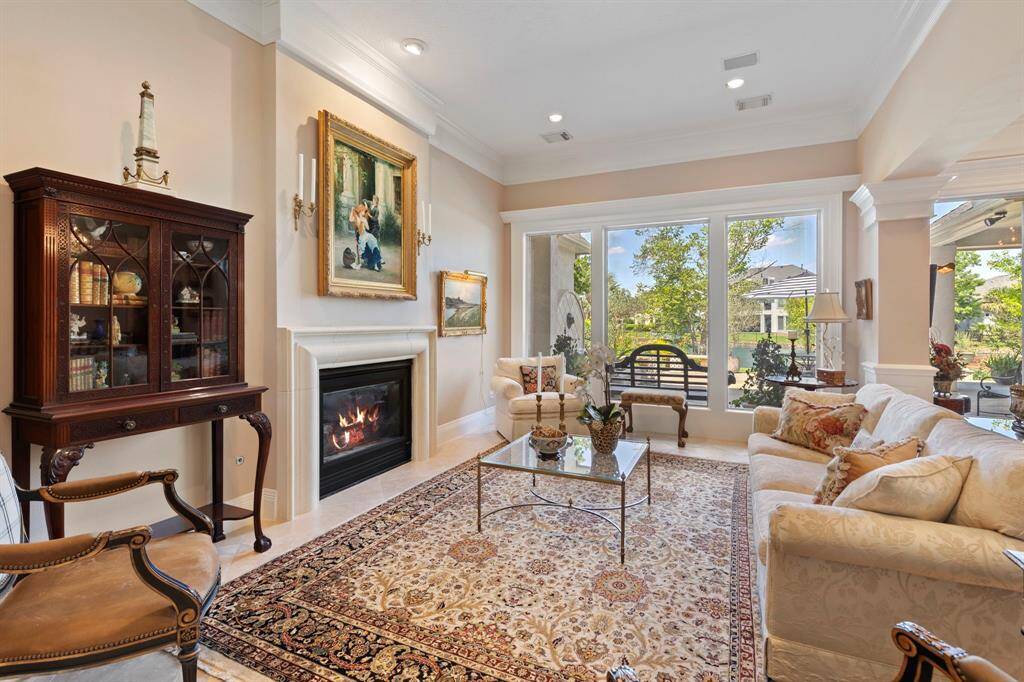 This elegant living room features a cozy fireplace, large windows with garden and lake views. This room is dripping in sophisticated ambiance.