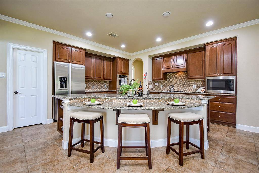 A spacious island with bar seating defines this kitchen, featuring lower cabinetry and cleverly integrated open shelving. This is a space equally suited to weekday breakfasts and festive weekend cooking.