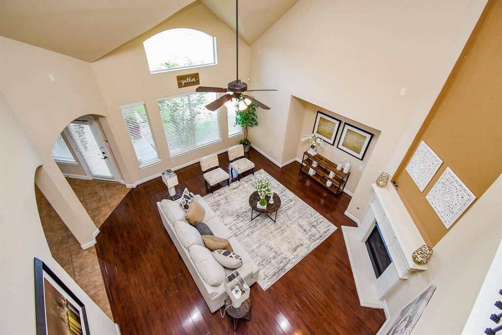 From above, the living room reveals its full scale—towering windows, fireplace, and visual access to the kitchen below—emphasizing the openness and architectural detailing that define the home.