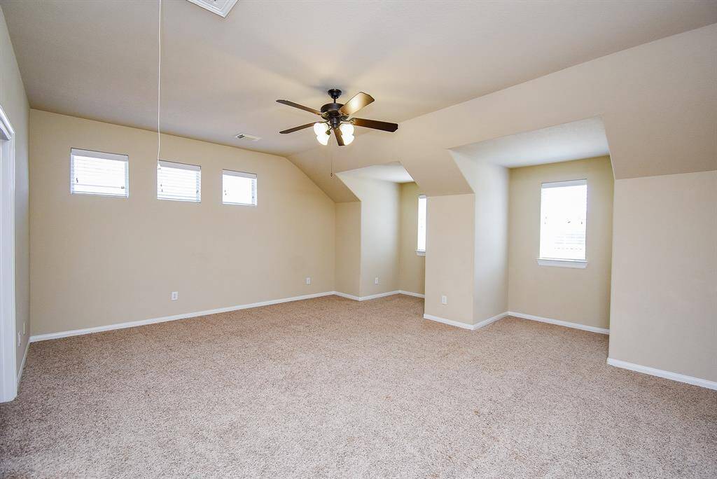 This expansive upstairs area features soft carpeting and unique recessed walls with windows that brighten the space—perfect for media, games, or creative endeavors.
