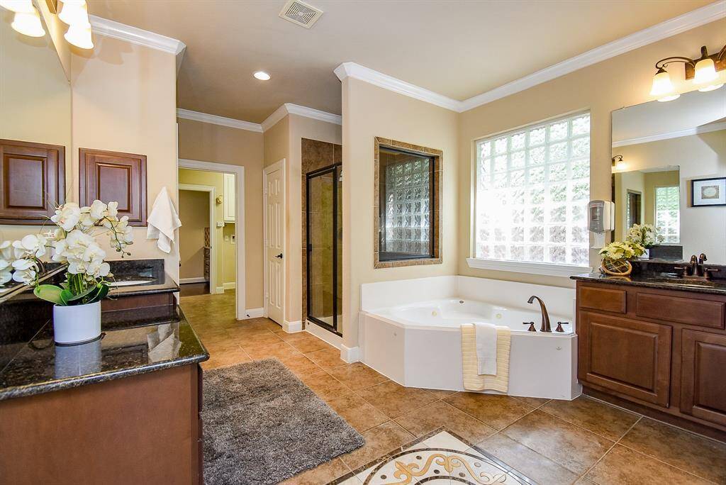 Finished with elegant tiling, the primary bathroom features dual vanities, a soaking tub, and a separate glass-enclosed shower. The thoughtful layout and details offer everyday luxury.