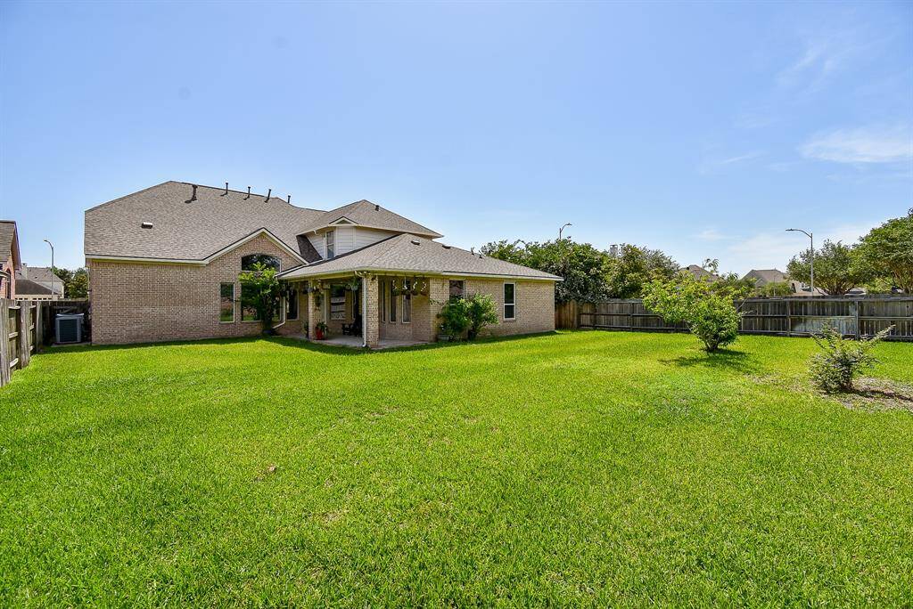 A covered patio at the rear of the home offers the ideal spot for shaded relaxation or outdoor dining, overlooking the backyard and perfectly blending indoor-outdoor living.