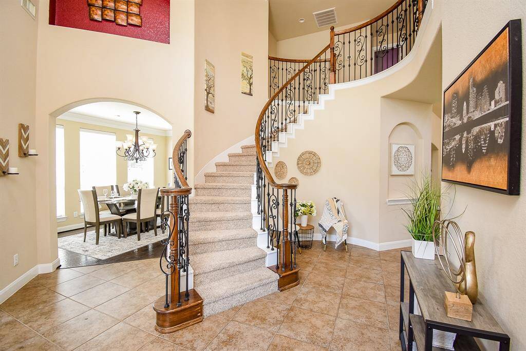 Just beyond the front door, a gracefully curved staircase adds sculptural drama to the entry. Sightlines extend toward the formal dining space, and subtle architectural curves carry your gaze upward and inward.