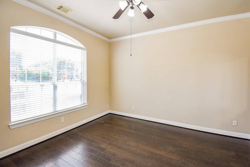 Anchored by a large arched window and smooth wood flooring, this bright space offers flexible use—perfect for a study, guest retreat, or reading lounge—bathed in morning light.