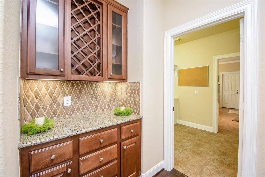 This butler’s pantry features a built-in wine rack, granite countertop, and glass-front cabinetry that beautifully displays your favorite pieces while streamlining service.