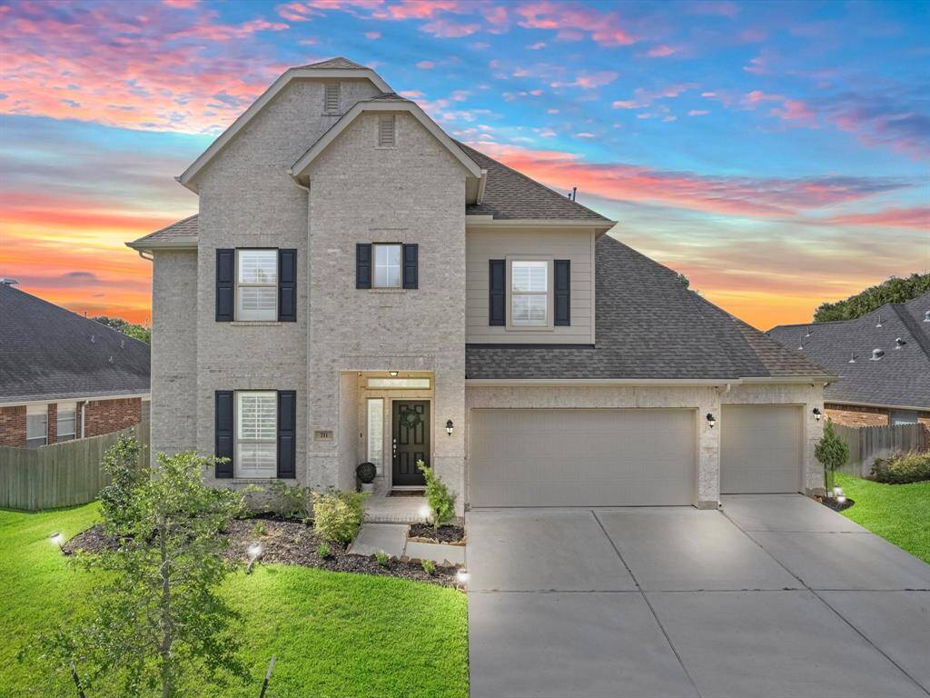 This photo showcases a modern two-story house with a clean, light brick exterior and dark shutters. It features a spacious three-car garage, well-maintained lawn, and a welcoming front entrance. The sky is beautifully vibrant, enhancing the home's curb appeal.