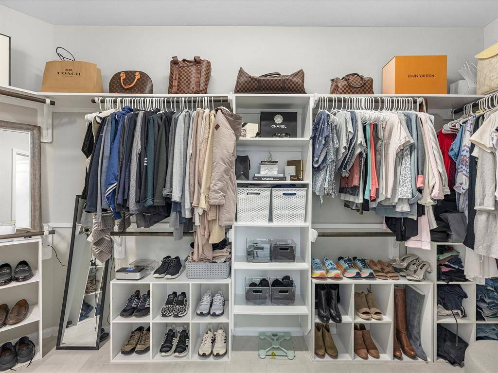 This photo showcases a spacious, well-organized walk-in closet with ample shelving, hanging space, and storage for shoes and accessories. Perfect for efficient storage and easy access to clothing and personal items.