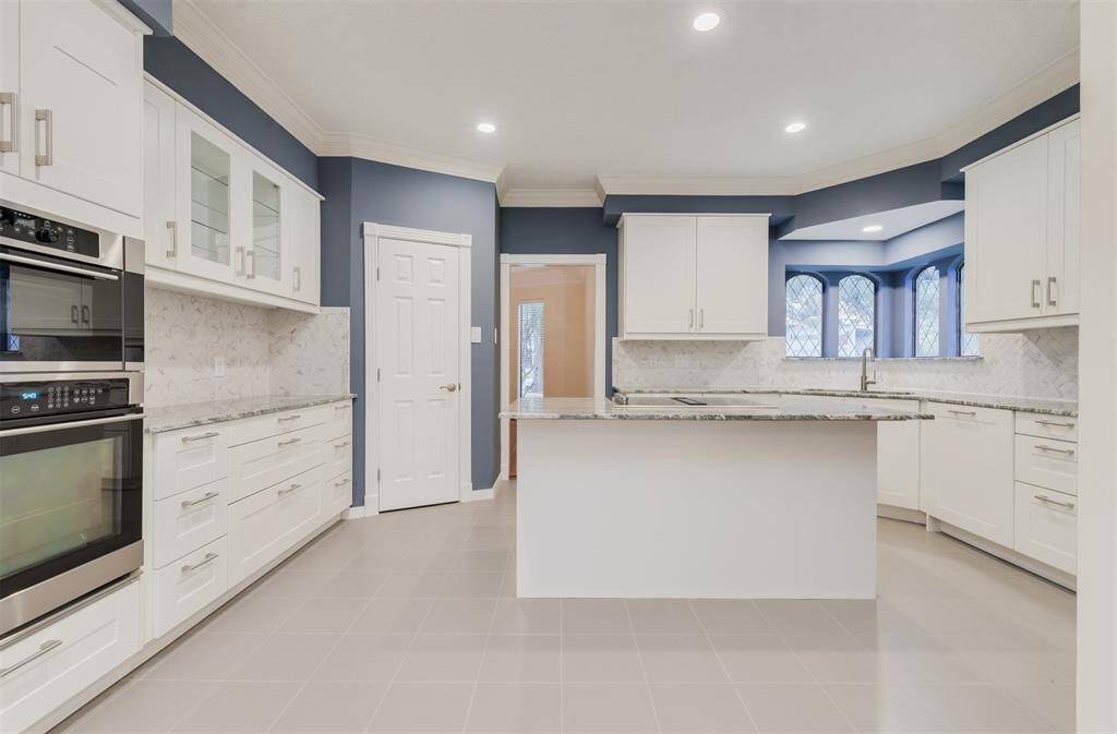 Newly remodeled island kitchen boasts all new white cabinets, some with glass inserts for displaying dishes.