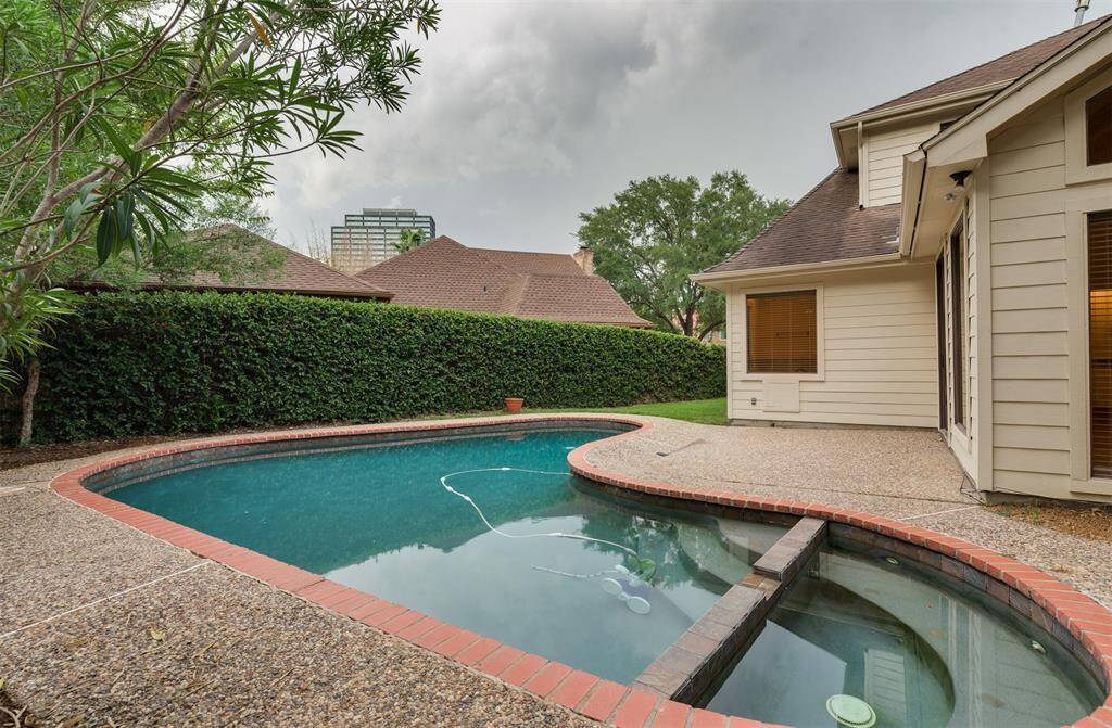 This L-shaped pool has an attached hot tub. A vine covered fence adds greenery and privacy.