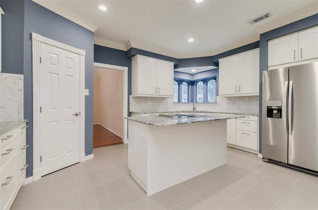 Easy to maintain grey tile floors accent the white cabinets and Granite counters. New side by side stainless steel refrigerator is included with Lease.