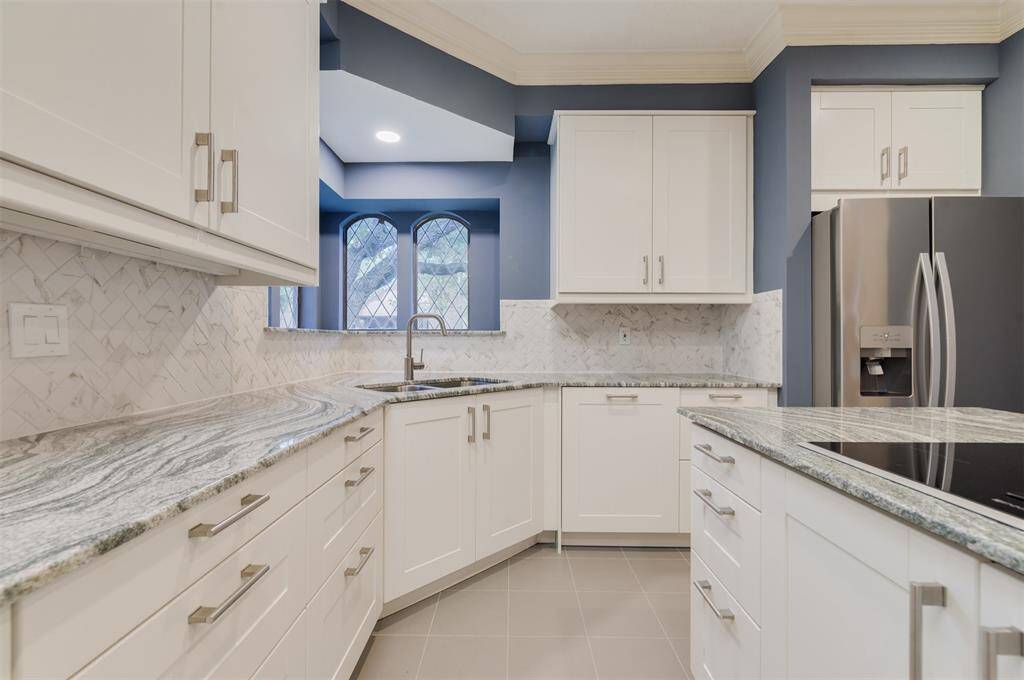 Close up view of the grey toned Granite counters and solid wood cabinets. The Herringbone back splash is gorgeous!