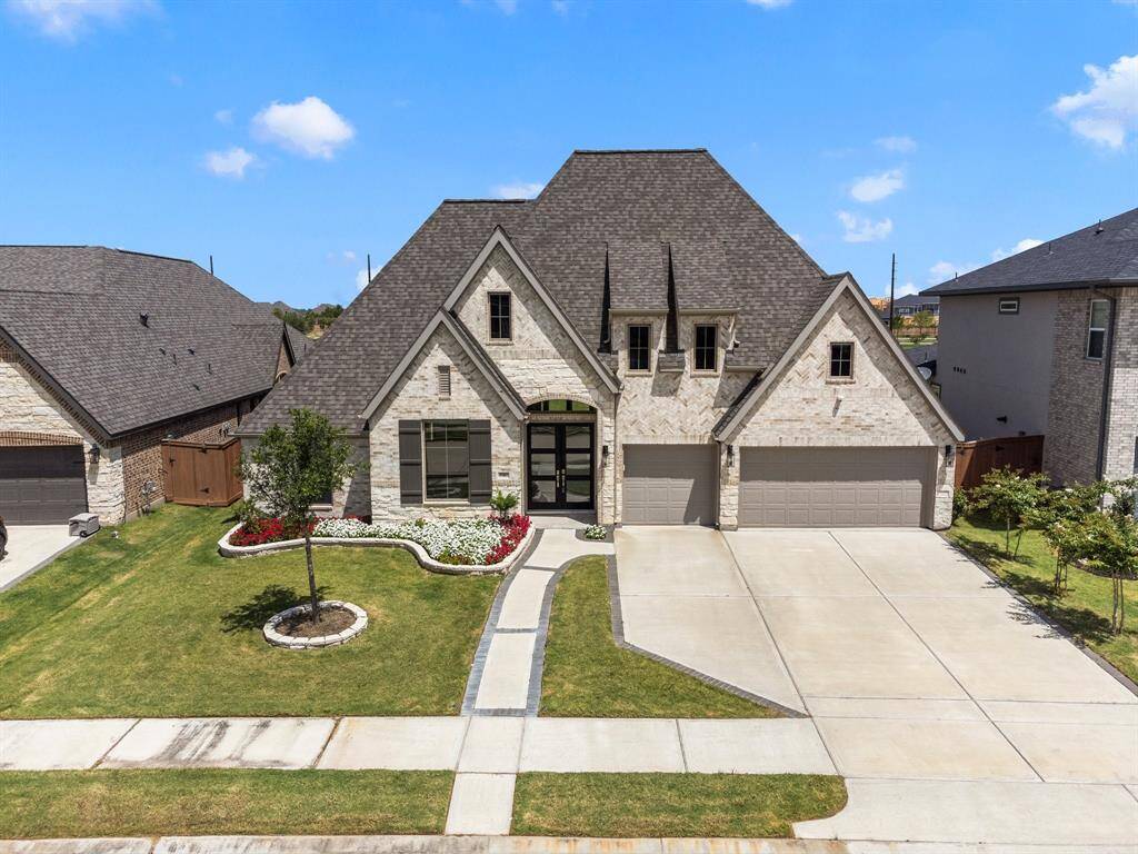 This is a spacious, modern single-family home featuring a  Brick and stone Elevation, steep gabled roofs, and a three-car garage. curb appeal  is complemented by a landscaped garden.