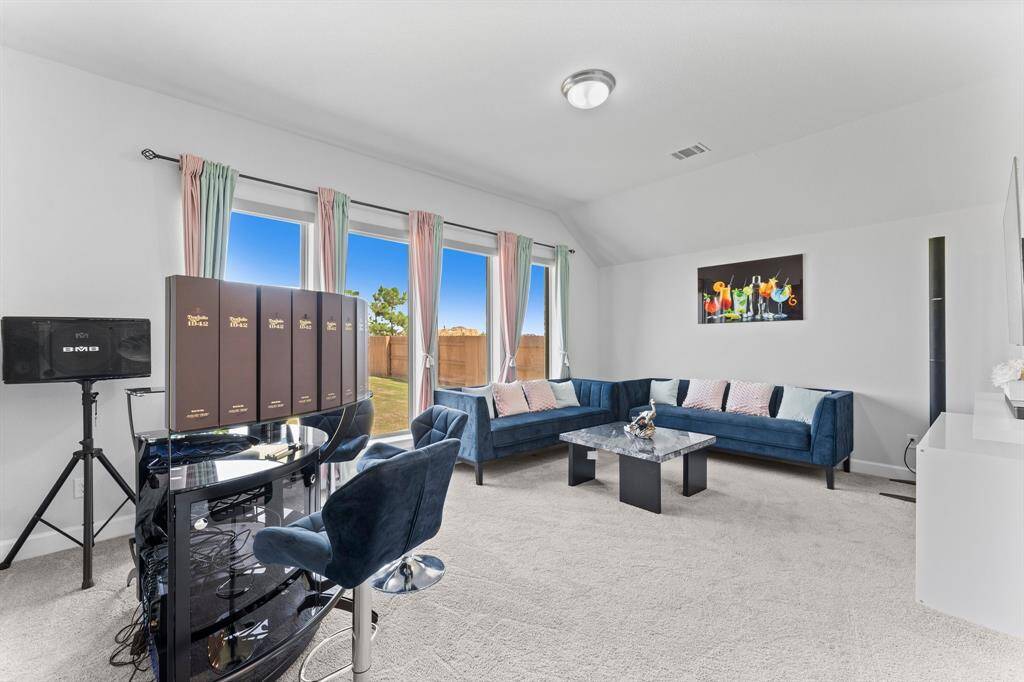 This is a bright and contemporary game-room The room is well-lit with natural light from large windows that offer a view of a fenced backyard. The space is accented with neutral colors  and has a cozy, yet stylish vibe.