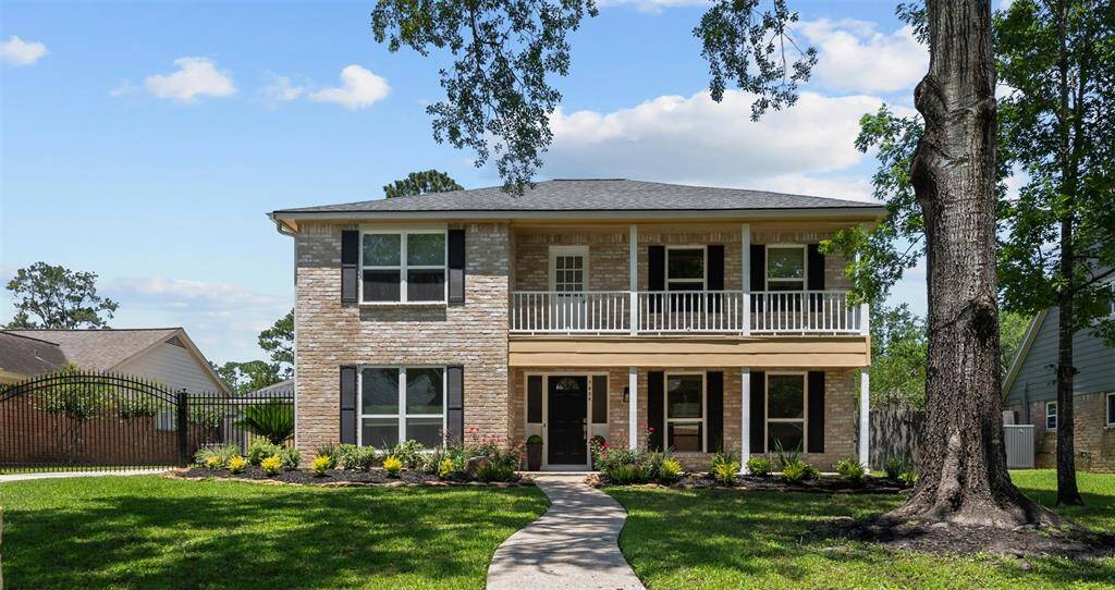 Gorgeous two-story brick home with a covered balcony, manicured landscaping and charming curved walkway leading to the front door.